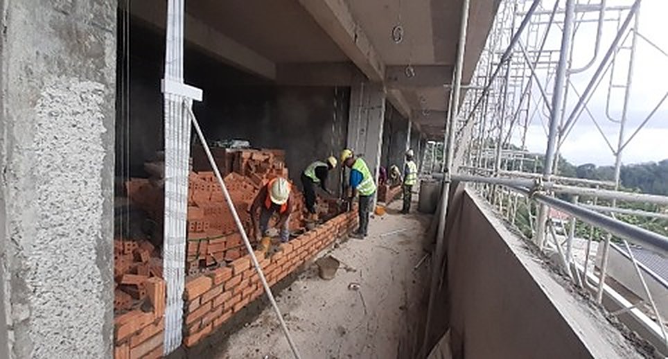 Crew laying brick with scaffold alongside