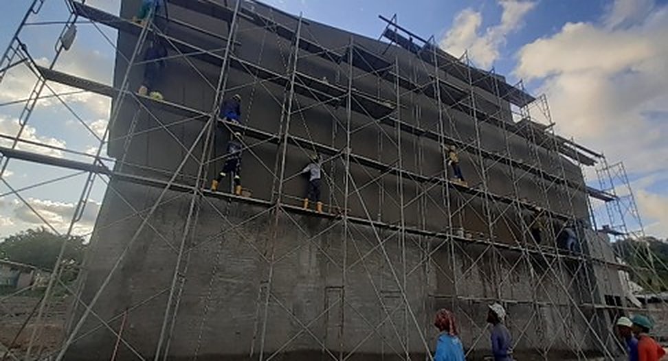 Workers on facade scaffold against blue sky